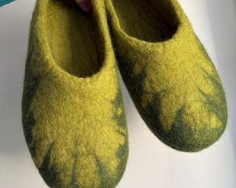 May include: A pair of felted wool slippers in a vibrant lime green and deep forest green colour palette. The slippers feature a seamless, rounded toe design with a textured, fuzzy surface and a slip-on style with an open top opening.