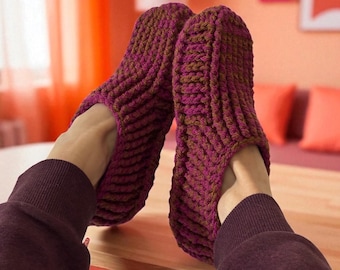 May include: Hand-knitted slippers in shades of purple and brown. The slippers have a ribbed texture and are designed to cover the entire foot. The image shows the slippers being worn, suggesting comfort and warmth. The background is a warm, inviting color.