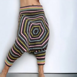 Könnte beinhalten: Eine Hose mit tiefem Schritt aus dunkelgrauem Garn mit horizontalen Streifen in Hellrosa, Hellblau und Limettengrün. Das Kleidungsstück weist ein markantes, sechseckiges Häkelmuster auf der Vorderseite sowie einen gerippten Bund und Beinabschlüsse auf.