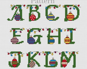 Puede incluir: Patrón de punto de cruz para las letras A a la M con luces de Navidad y adornos. Los adornos son rojos, verdes, amarillos y azules.
