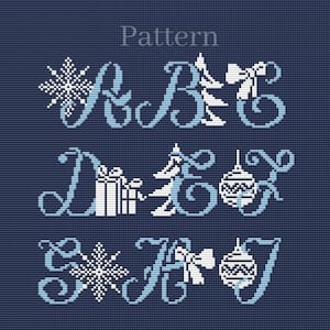 May include: A cross-stitch pattern on a navy blue background. The word "Pattern" is at the top. The design features the letters A through J, with holiday-themed embellishments like snowflakes, Christmas trees, gift boxes, bows, and ornaments.