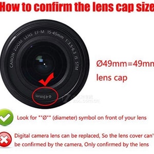 May include: A black camera lens with the text "Canon Zoom Lens EF-M 15-45mm 1:3.5-6.3 IS STM" printed on the side. The lens has a diameter of 49mm, as indicated by the symbol "&Oslash;49mm=49mm lens cap".