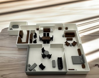 May include: A white model of a floor plan with furniture, including a dining table with chairs, a couch, a bed, and a coffee table.