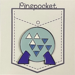 May include: A blue and white enamel pin shaped like a sphere with a pattern of triangles. The pin has two purple legs and the text "Pinspocket" is printed on the background.