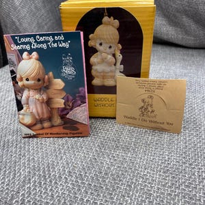 May include: A porcelain figurine of a young girl holding a goose. The figurine is part of the Precious Moments collection and is titled "Waddle I Do Without You". The figurine is a 1993 Symbol of Membership Figurine.