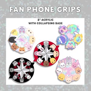 May include: A collection of 2-inch acrylic fan phone grips with collapsing bases. The grips feature colorful cartoon animal faces and the text "FAN PHONE GRIPS". The designs include a variety of animals and starburst patterns.
