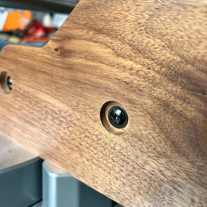 Peut inclure: Gros plan sur une surface en bois brun fonc&eacute; avec une vis noire dans un trou. Le bois a un grain naturel.