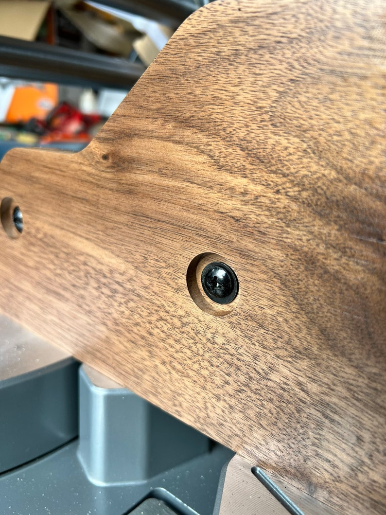 Peut inclure: Gros plan sur une surface en bois brun fonc&eacute; avec une vis noire dans un trou. Le bois a un grain naturel.