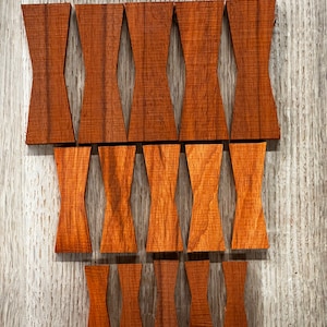 May include: A set of 12 wooden bow tie shapes, all in a rich brown colour. The bow ties are arranged in two rows, with six in each row. The bow ties are all the same size and shape, and they have a smooth, polished finish.