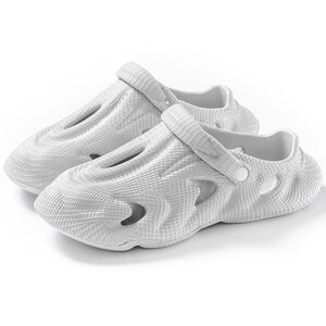 May include: A pair of white slip-on clogs featuring a textured grid pattern across the exterior surface. The footwear includes multiple side ventilation cutouts and a pivoting heel strap secured with a circular white button on each side.