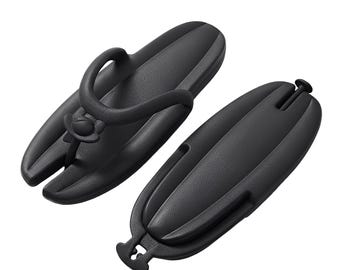 May include: A pair of black, elongated, oval-shaped sandals with a textured surface. One sandal features a central thong strap with a small, circular accent at the base, while the other is shown from the underside, revealing a smooth, solid base.