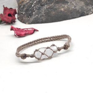 K&ouml;nnte beinhalten: Ein braunes geflochtenes Armband mit einem wei&szlig;en Kristall, der in einen Makramee-Knoten eingewickelt ist.