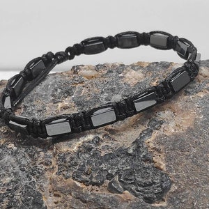 May include: A black bracelet with black square beads and black cord.