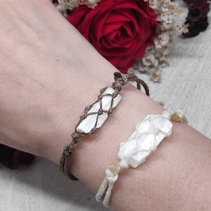 K&ouml;nnte beinhalten: Zwei Armb&auml;nder mit wei&szlig;en Selenit-Kristallsteinen, die in braunes Band gewickelt sind. Die Armb&auml;nder werden am Handgelenk einer Person getragen.