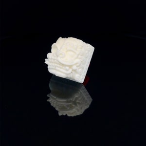 May include: White keycap with a detailed, three-dimensional design of a mythical creature's face. The keycap is square and has a red accent on the bottom.