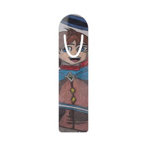 May include: A colorful bookmark featuring a hand-drawn illustration of a smiling character with brown hair, blue eyes, and a blue cape. The bookmark has a white background and a curved top.