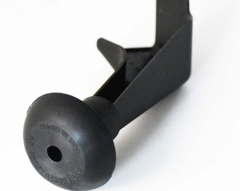May include: Black plastic bottle stopper with a suction cup base and a triangular shaped top. The base has the text "MADE IN USA" printed on it.