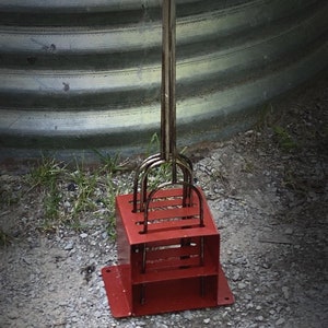 May include: A red metal tool with multiple metal hooks attached to a long metal rod. The tool is designed to hold and lift objects.