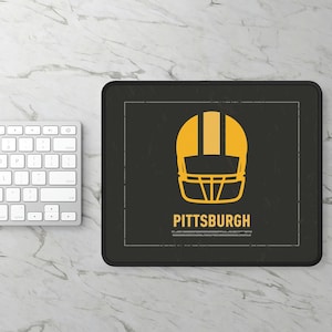 May include: Black mouse pad with a yellow and black football helmet graphic and the text "PITTSBURGH" in white.