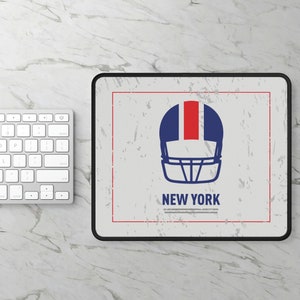 May include: A white mousepad with a black border features a distressed graphic of a blue and red football helmet with a white facemask. The text "NEW YORK" is printed below the helmet.