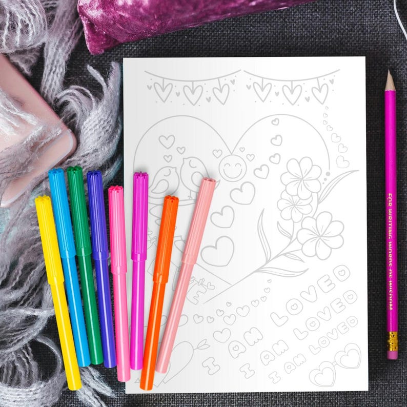 May include: A coloring page with a heart shape and the text "I am loved" repeated three times. The heart is decorated with flowers, birds, and hearts. The page is surrounded by a set of ten colorful markers.