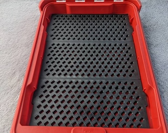 Puede incluir: Caja de almacenamiento de plástico roja con tapa transparente y un inserto de espuma negra con un patrón de cuadrícula.
