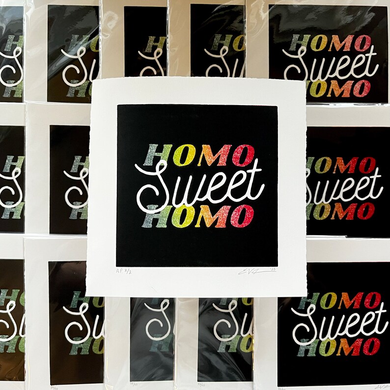 homo sweet homo linocut print laying on top of a stack of other prints