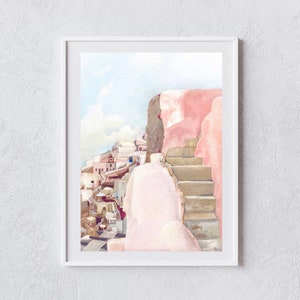 May include: A framed watercolor painting depicting a Mediterranean coastal scene with a prominent pink wall and stone staircase in the foreground, overlooking a cluster of white buildings under a pale blue sky with soft clouds in the distance.