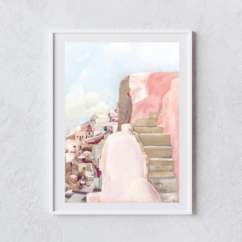 May include: A framed watercolor painting depicting a Mediterranean coastal scene with a prominent pink wall and stone staircase in the foreground, overlooking a cluster of white buildings under a pale blue sky with soft clouds in the distance.