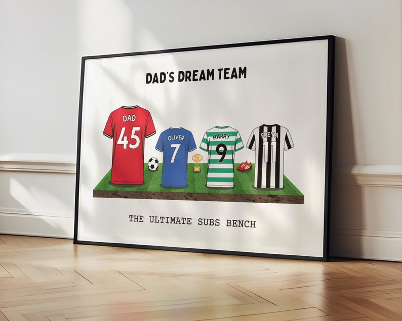 May include: Framed print featuring four soccer jerseys on a green field. The jerseys are red, blue, green, and black and white striped. Text at the top reads "DAD'S DREAM TEAM" and at the bottom "THE ULTIMATE SUBS BENCH".