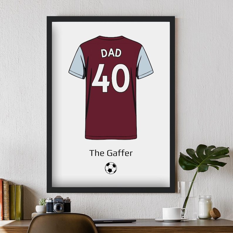 May include: Framed print featuring a maroon and light blue soccer jersey with the word "DAD" above the number "40". Below the jersey is the text "The Gaffer" and a soccer ball graphic. The jersey is centered on a white background.