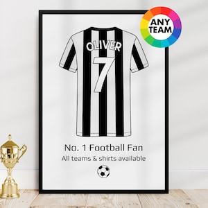 May include: Framed black and white football jersey print with the name "Oliver" and the number "7". The print includes the text "No. 1 Football Fan" and a soccer ball graphic. A gold trophy is in the foreground.
