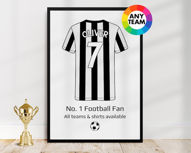May include: Framed black and white football jersey print with the name "Oliver" and the number "7". The print includes the text "No. 1 Football Fan" and a soccer ball graphic. A gold trophy is in the foreground.