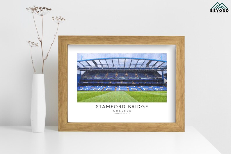 May include: A framed print of Stamford Bridge, the home of Chelsea Football Club in London, England. The print features a watercolor-style illustration of the stadium with the text "Stamford Bridge, Chelsea, London, England" below the image.