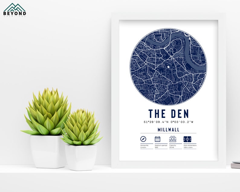 Pu&ograve; includere: Una stampa incorniciata bianca con una mappa blu di Millwall, Londra, Inghilterra. La mappa &egrave; in un cerchio con il testo "THE DEN" e le coordinate "51&deg;29'09.4"N 0&deg;03'03.2"W". Il testo "MILLWALL" &egrave; sotto le coordinate.