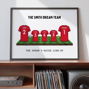 May include: Framed print featuring red soccer jerseys with names and numbers, arranged on a green field. The text reads "THE SMITH DREAM TEAM" and "THE DREAM 5-ASIDE LINE-UP". A soccer ball and trophy are also included.