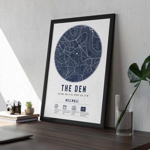 Pu&ograve; includere: Una stampa incorniciata nera con una mappa blu navy di Millwall, Londra. La stampa ha il titolo "The Den" e le coordinate "51&deg;29' 08.4" N 0&deg;03' 03.2" W".