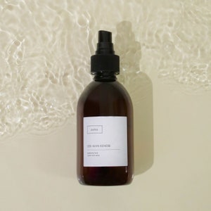 Pu&ograve; includere: Un flacone di vetro marrone con un ugello spray nero. Il flacone ha un'etichetta bianca con il testo "asha" e "OBI-WAN KENOBI" stampato su di essa. L'etichetta dice anche "powered by hand" e "ambient room spray".