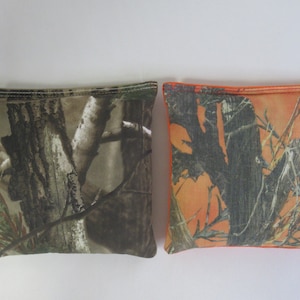 May include: Two bean bags with camouflage patterns. One bean bag is brown and green, the other is orange and green.