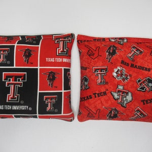 May include: Two red and black bean bags with the Texas Tech University logo and the words "Red Raiders" and "Texas Tech University".