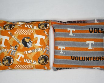 May include: Two orange and gray bean bags with the University of Tennessee Volunteers logo and the words "VOLS" and "Tennessee".