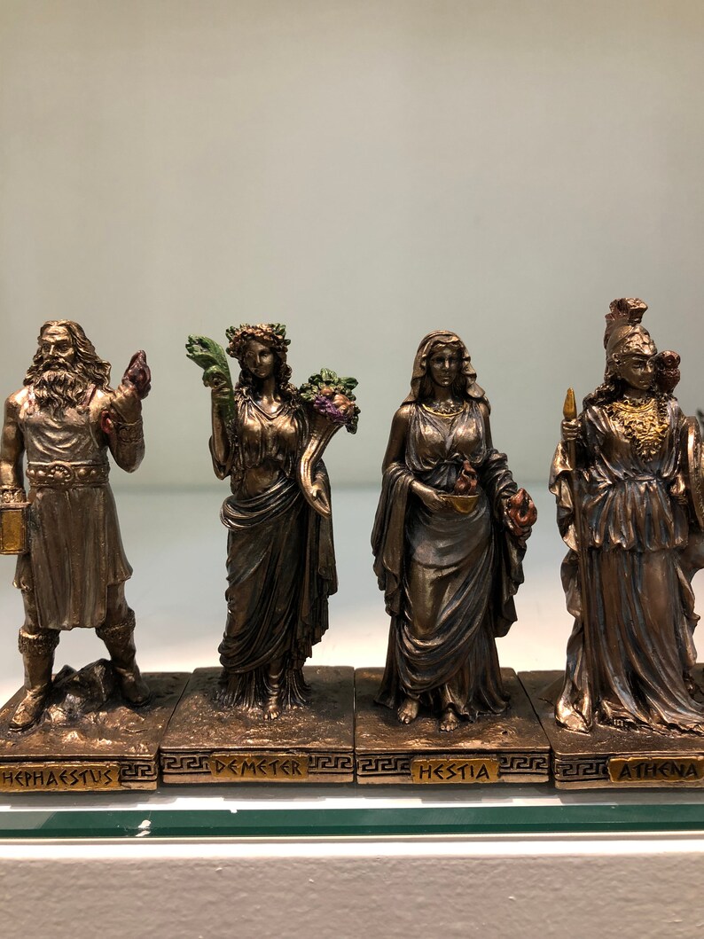 May include: Set of five bronze Greek goddess figurines, each standing on a base with their name inscribed in Greek. The goddesses are Hephaestus, Demeter, Hestia, and Athena.
