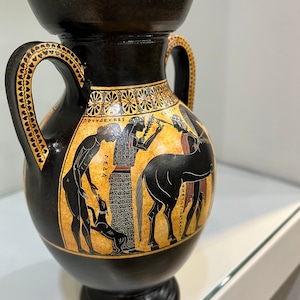 May include: Black and red Greek pottery vase with two handles and a scene painted on the side. The scene depicts a woman holding a branch, a man with a dog, and a horse. The text on the vase reads "&Pi;&Omicron;&Upsilon;&Sigma;&Epsilon;&Nu;&Iota;&Kappa;&Epsilon;&Sigma;" and "&Delta;&Eta;&Mu;&Epsilon;&Tau;&Omicron;&Pi;&Iota;&Alpha;&Sigma;&Kappa;&Alpha;&Nu;&Delta;&Omicron;&Sigma;".