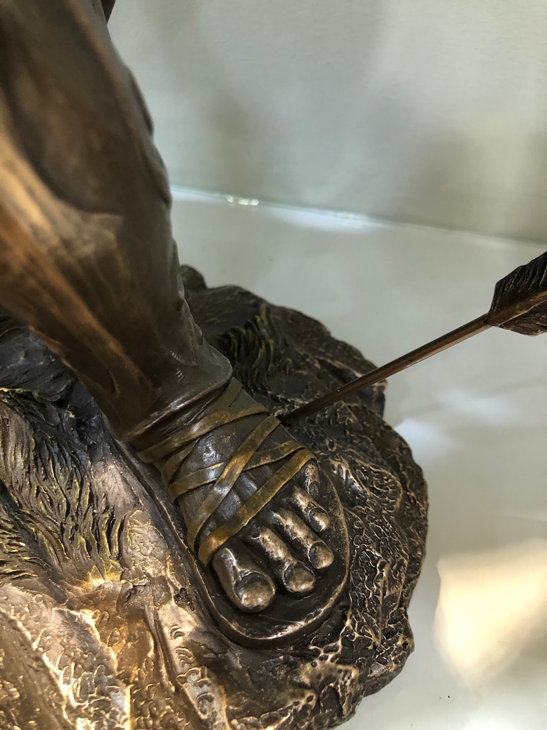 May include: Bronze sculpture of a man with an arrow through his foot. The sculpture is detailed and shows the man's foot bound with straps.