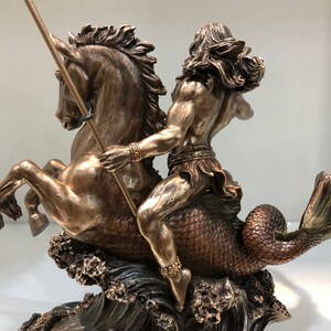 K&ouml;nnte beinhalten: Bronzeskulptur, die eine mythologische Figur zeigt, die ein Seepferd reitet. Die Figur mit langem Haar und einem Speer ist muskul&ouml;s und detailliert. Das Seepferdchen hat einen Pferdekopf und einen Fischschwanz, mit Wellen an der Basis.
