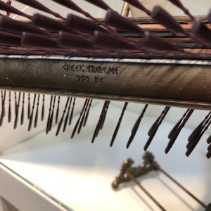 Puede incluir: Primer plano de una maqueta de una trirreme griega, un tipo de barco de guerra griego antiguo, con la inscripci&oacute;n "GREEK TRIREME 505 BC" en el lateral.