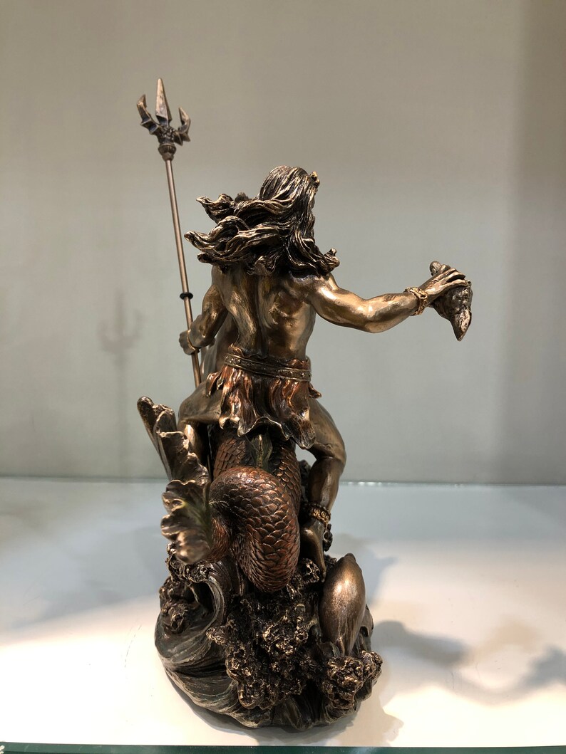 K&ouml;nnte beinhalten: Bronzefarbene Statue einer mythologischen Figur, die einen Dreizack und einen abgetrennten Kopf h&auml;lt. Die Figur hat lange Haare und sitzt auf einem Seeungeheuer. Die Statue ist detailliert und steht auf einem Sockel, der Meereswellen darstellt.