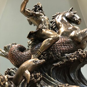 K&ouml;nnte beinhalten: Bronzestatue von Poseidon, der ein Seepferd reitet und eine Muschel hochh&auml;lt. Ein Delphin schwimmt in den Wellen darunter. Die Statue hat komplizierte Details und ist auf einem Sockel mit dem Namen "Poseidon" montiert.