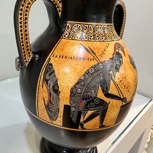 May include: Black and orange Greek amphora with two handles, a black and white painted scene of a warrior and a woman, and the text "EXSEKIASEMOIESE" and "TESANAPA".