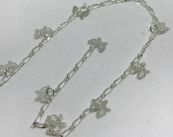 May include: A silver chain anklet with multiple butterfly charms. The anklet has a lobster clasp closure.